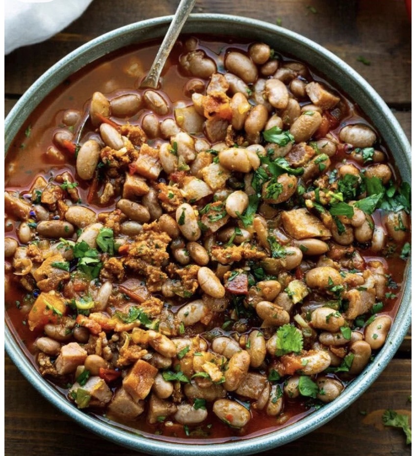 A rustic bowl of cowboy beans with chorizo and fresh cilantro — The Charro signature.
