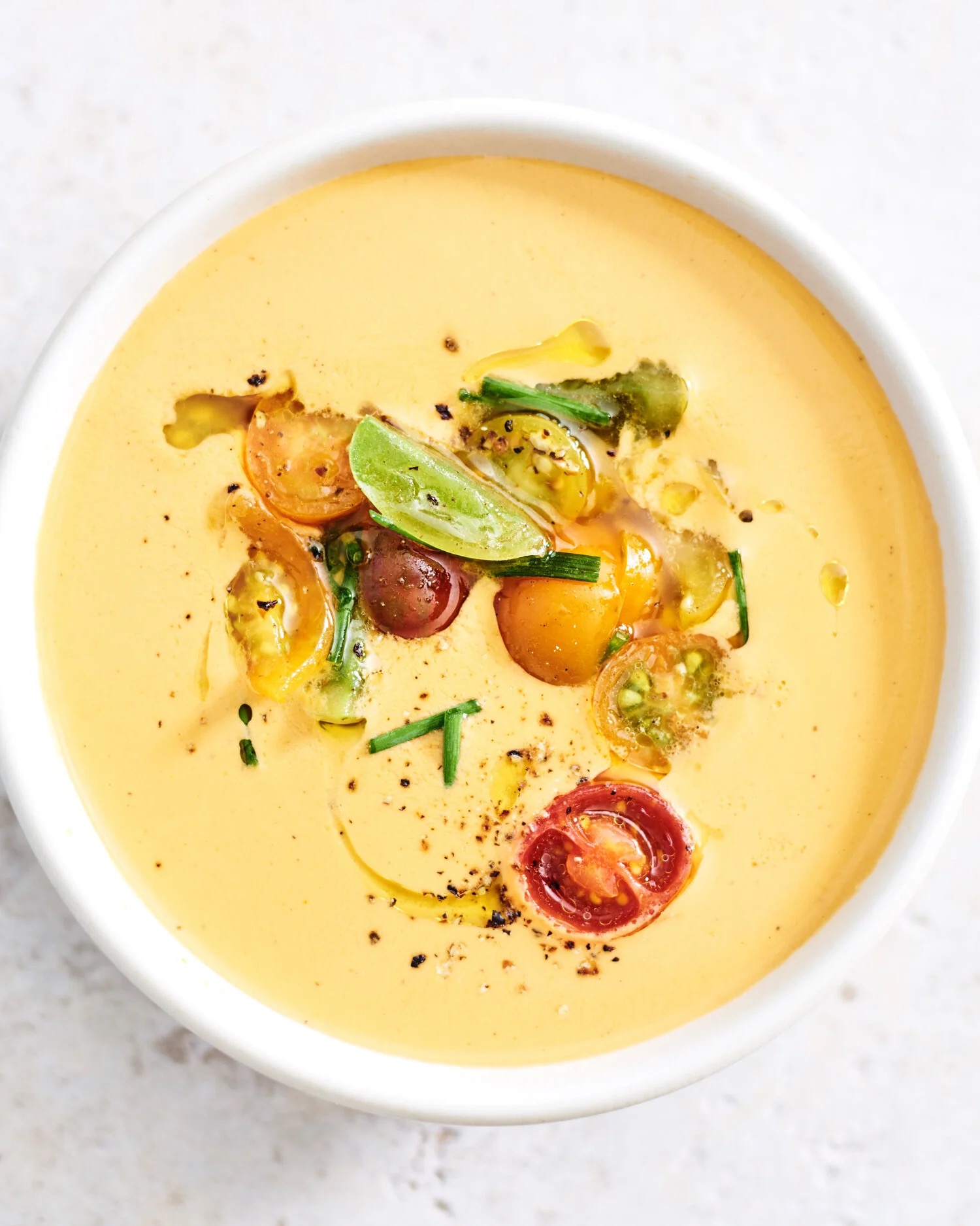 Chilled summer corn velouté with heirloom cherry tomatoes, basil oil, and chives.
