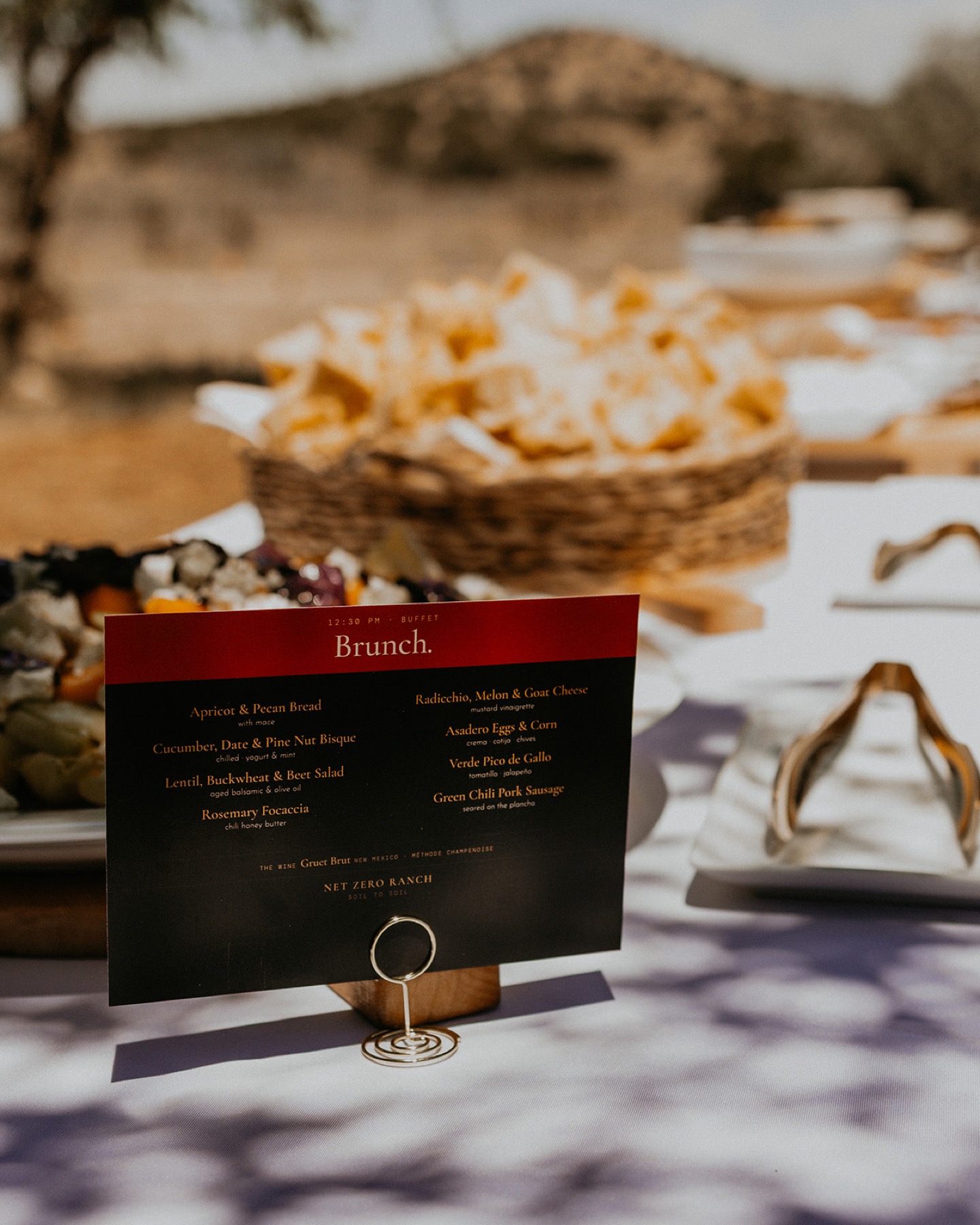 A Net Zero Ranch brunch menu card on a styled outdoor table against the ranch backdrop — a custom event.