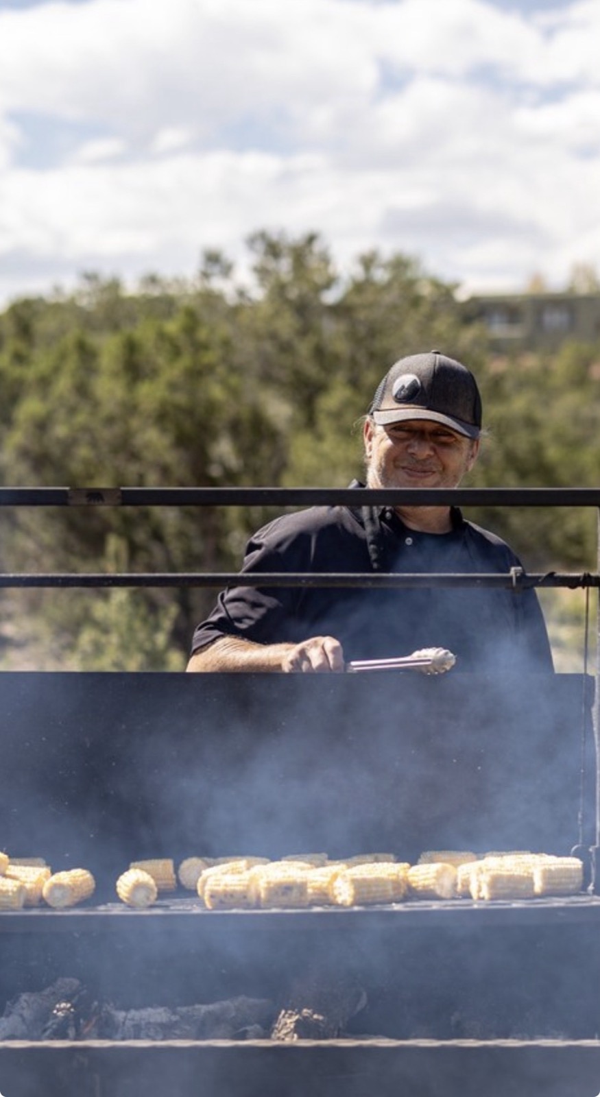A Net Zero Ranch cook grilling sweet corn over live fire.