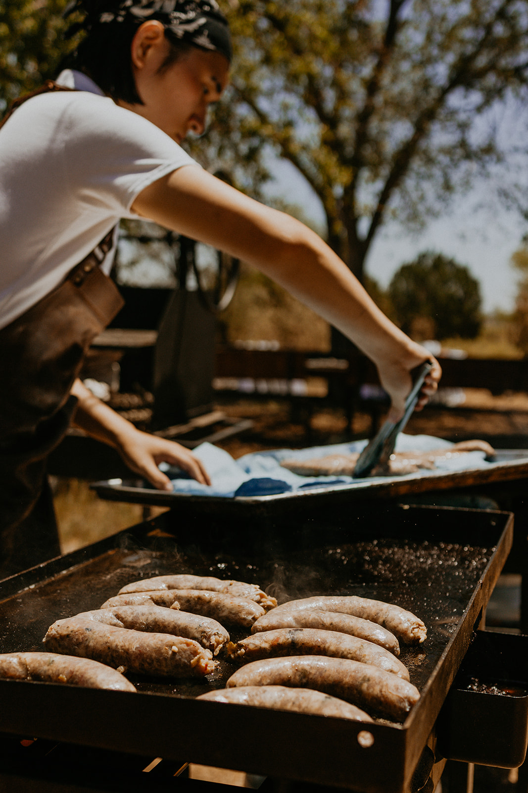 A Net Zero Ranch chef searing green-chile sausages on the plancha.