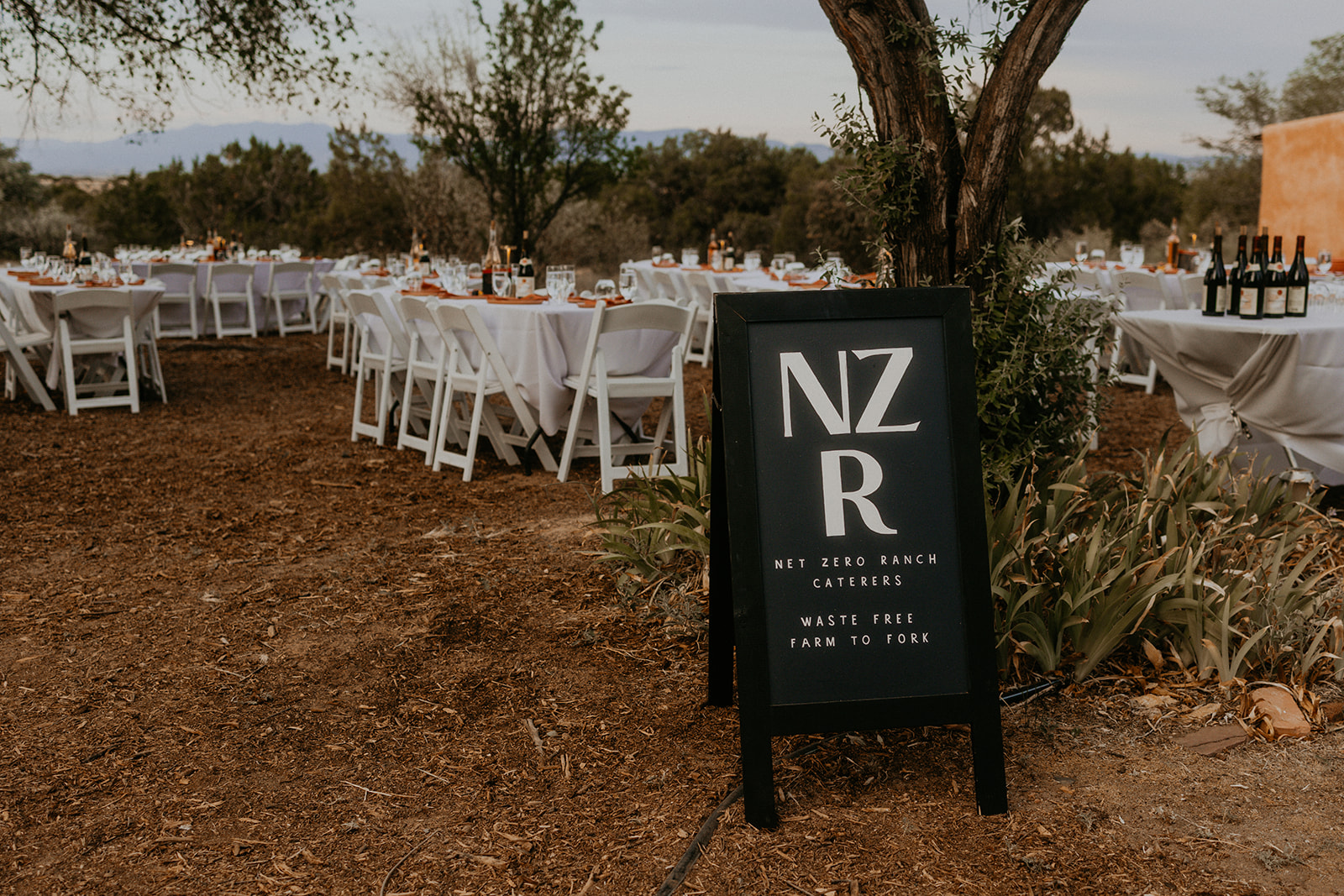 The Net Zero Ranch chalkboard sign beside styled reception tables at an outdoor event.