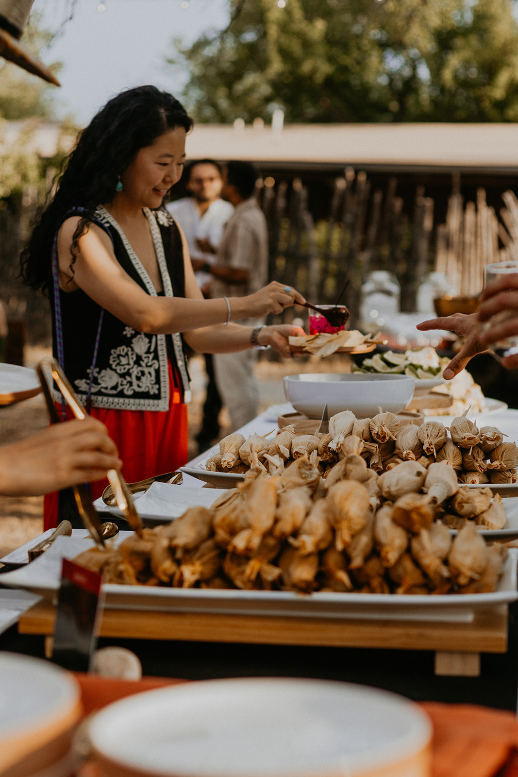 A guest serving herself at the Net Zero Ranch tamale buffet at an outdoor event.