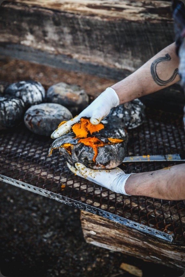 Fire-roasted winter squash, cracked open over the coals — The Asado table.