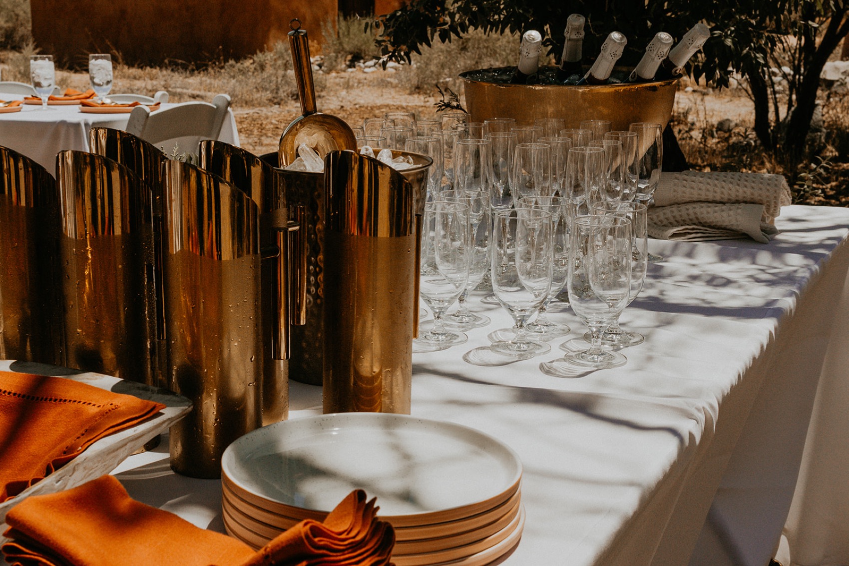 A styled beverage table with brass tumblers, champagne flutes and sparkling on ice.
