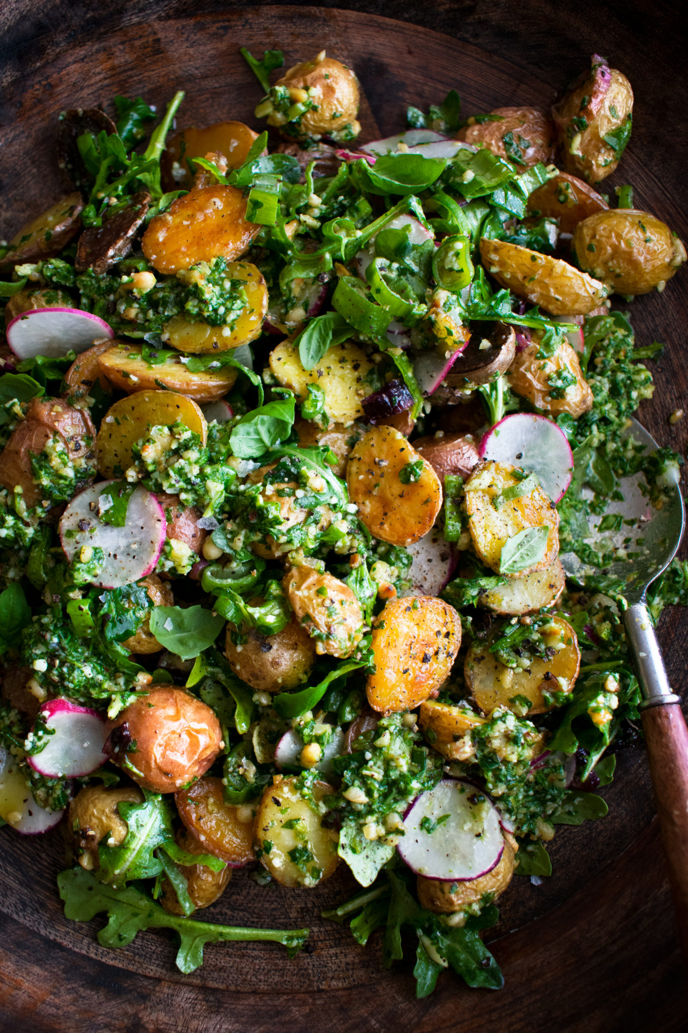 Roasted baby potatoes with arugula, radish, basil, and herb pesto in a wooden bowl — Retreat Chef table.