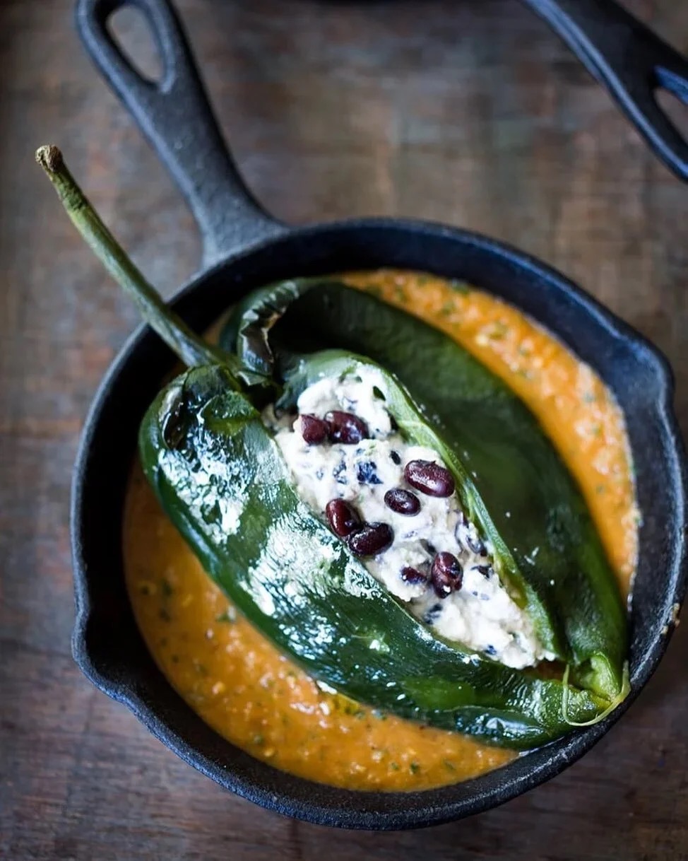 Roasted poblano stuffed with herbed goat cheese and black beans over chile-tomato salsa — cast-iron service.