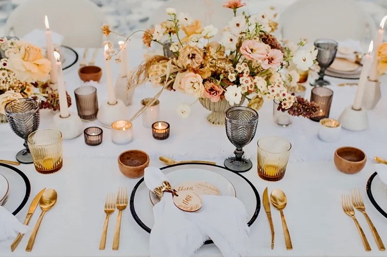 A Gaucho 5-course wedding tablescape — ivory linen, dusty pink and amber florals, smoky glass goblets, gold cutlery.