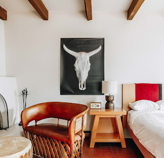 El Rey Court guest room — vigas, longhorn skull canvas, and refined Southwestern interior in Santa Fe.