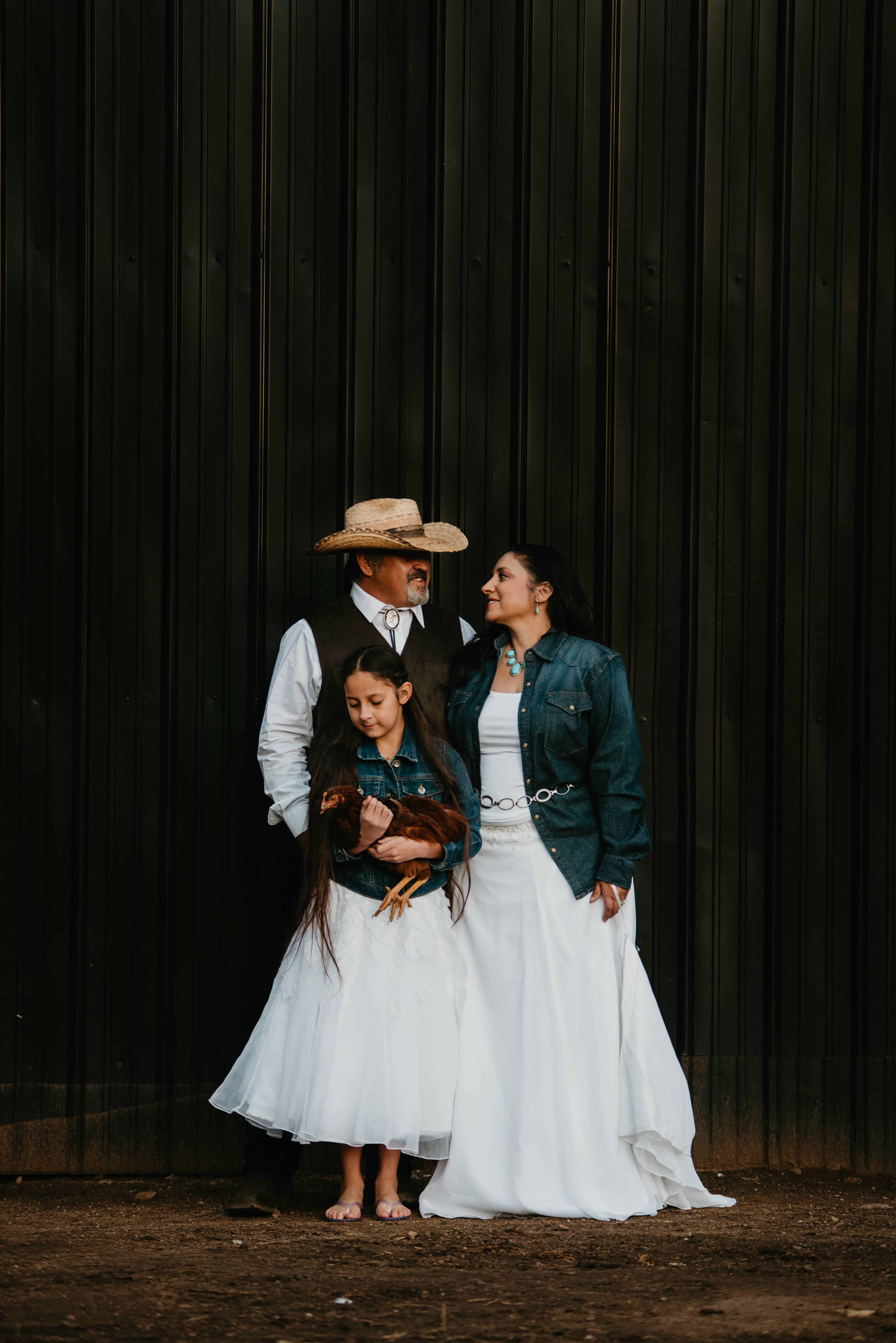 A New Mexico wedding family portrait — the parents, the daughter, and a backyard chicken — captured at an NZR-catered event.
